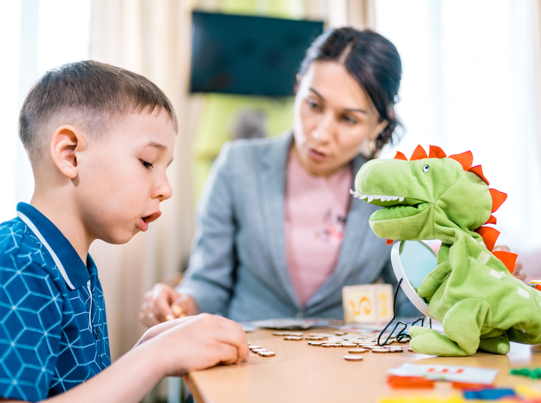 Unsere Therapieangebote für Kinder und Jugendliche, Bild von einem Jungen und einer Frau, die gemeinsam ein Spiel spielen